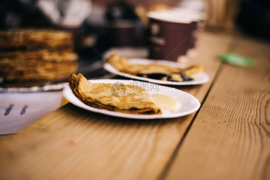 在马斯莱尼察节上男人在街上拿煎饼用浓缩图片