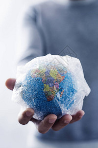 一个年轻的天主教男子的近身与一个世界地球包在他手上图片