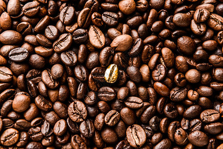 棕色咖啡豆中的一颗金色咖啡豆背景图片