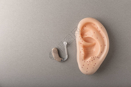 灰色背景下的助听器和耳朵模型图片