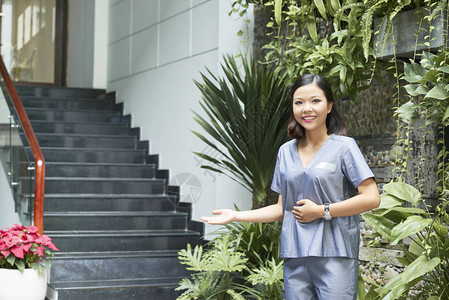 身穿制服微笑和邀请客户到健康中心去的亚洲女工人肖像图片