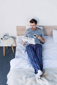 穿着睡衣的帅男躺在床上喝着咖图片