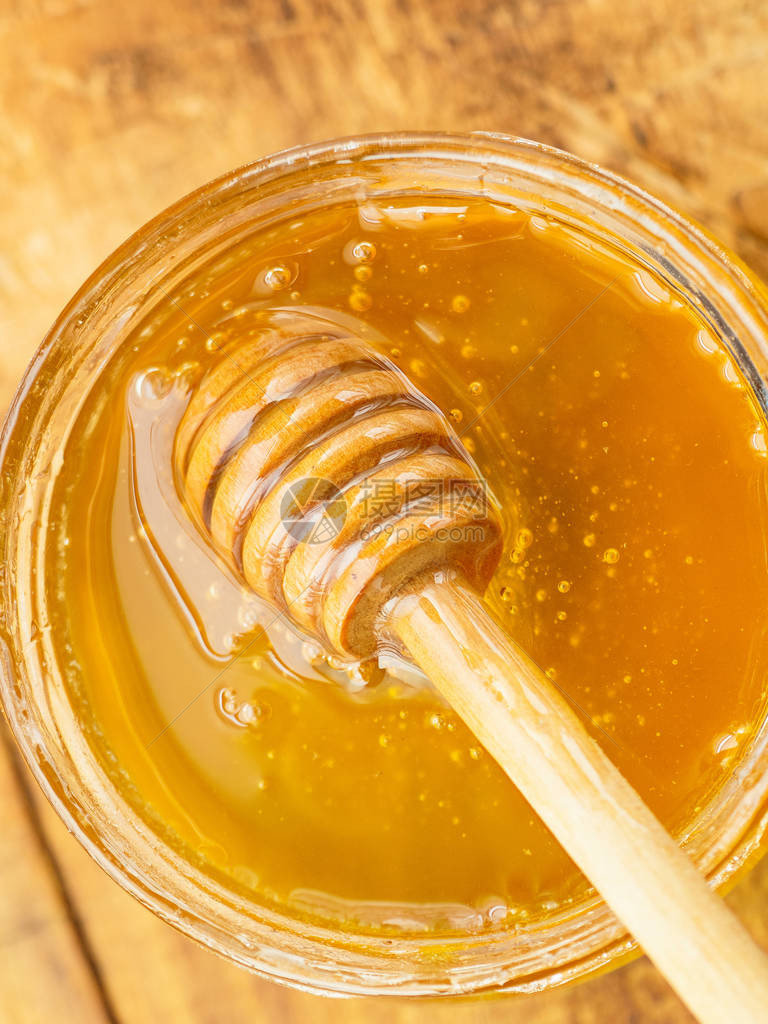 蜂蜜与木制搅拌器垂直图片