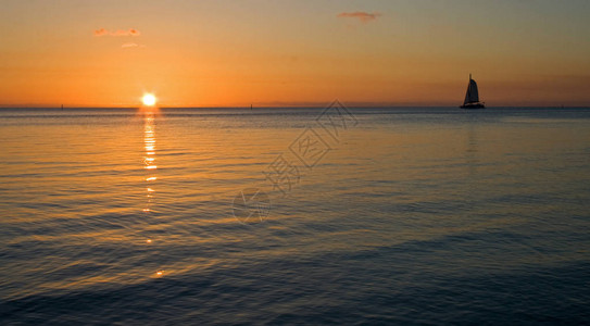 一艘帆船驶过热带日落图片