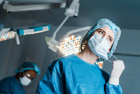 手术室穿制服的护士脱下医用口罩图片