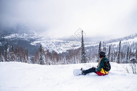 山里的女子滑雪板运动员坐在雪图片