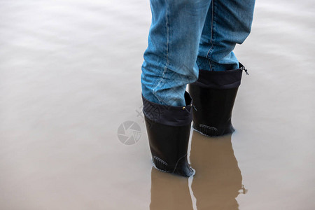 穿橡胶靴的人站在泥泞的水坑里图片
