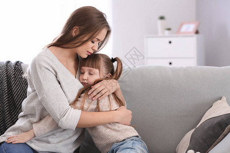 离婚后悲伤的女人坐在沙发上抱着女儿图片