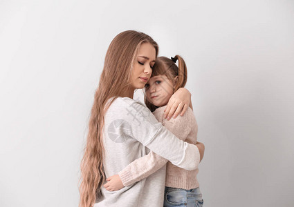 离婚后悲伤的女子在轻度背景下拥抱她女儿图片