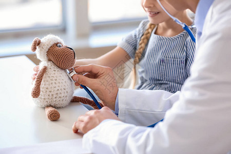 小儿科医生带玩具给小女孩展示如何在诊图片