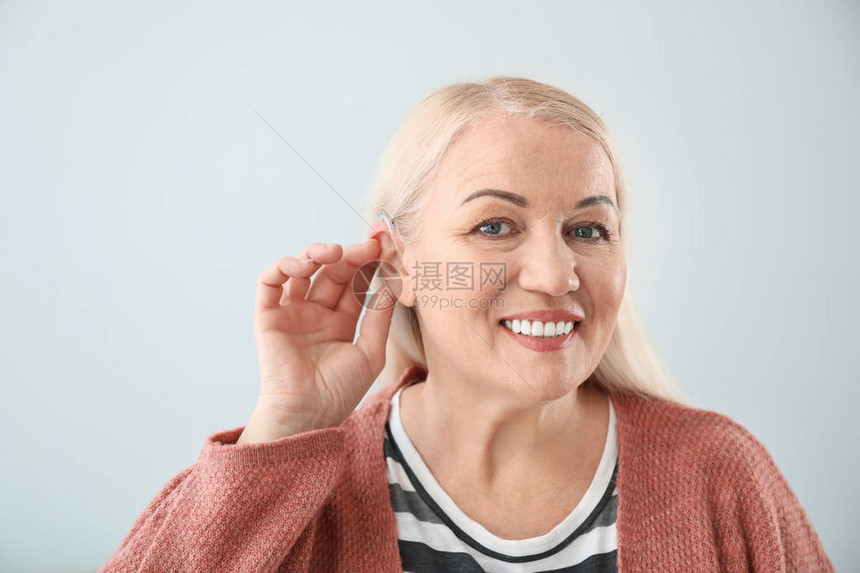 浅色背景下带助听器的成熟女图片