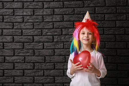 穿着明亮假发和深底气球的有趣的小女孩背景