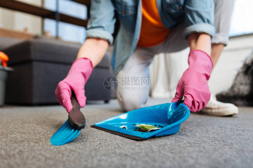 扫尘勤劳的女清洁工在打扫地板时戴着防护粉色手套图片