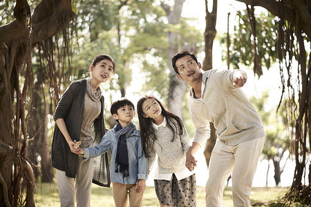 有两个孩子的亚洲家庭在公园里探图片