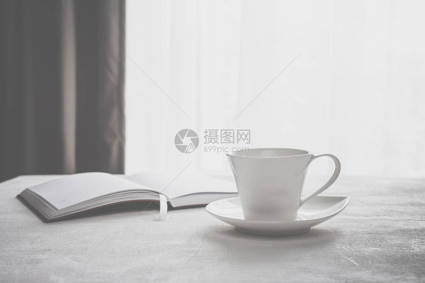 咖啡杯在窗前的桌子上一张格子笔记本图片