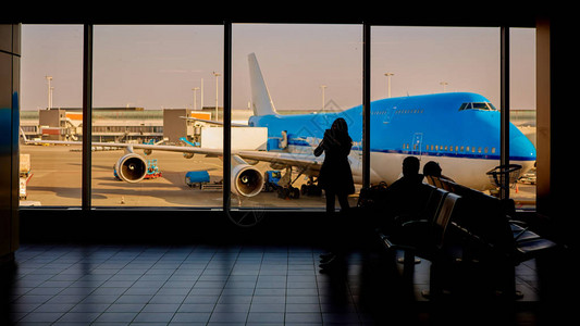 在机场等待离境的乘客携带行李的女旅客的周光照亮了她们图片