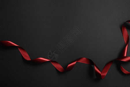 黑色背景的红色丝绸卷带顶部视图图片