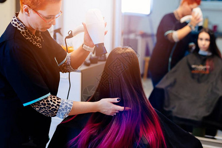 女理发师用吹发机烘洗客户头发在美容图片