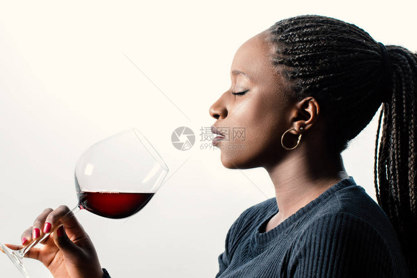 非洲女酒迷闻红酒芳香味的近距离旁观肖像长着卷发和眼睛的女人在白色背景图片