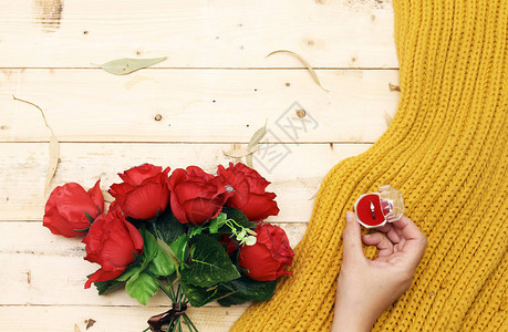 美丽的红玫瑰花朵紧的手握着一个戒指联盟盒子里有彩色芥子酱围图片