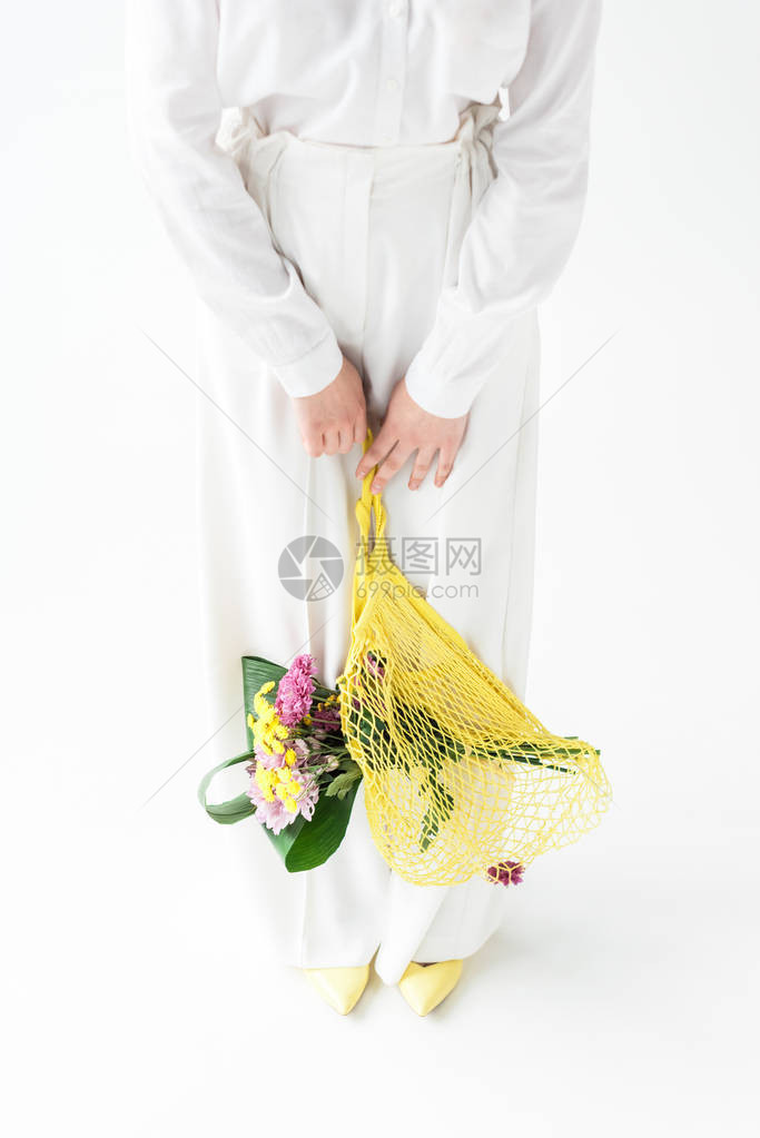 妇女站在白色上时拿着黄绳袋和野花的妇图片