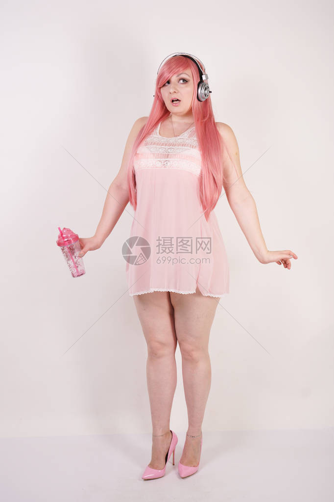 穿着粉红内衣带耳机的装扮和在白色工作室背景上玩游戏的超级超级羽图片