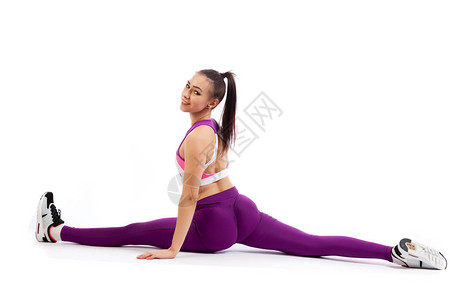 一位深色头发的女教练身穿运动型紫色短上衣和健身房图片