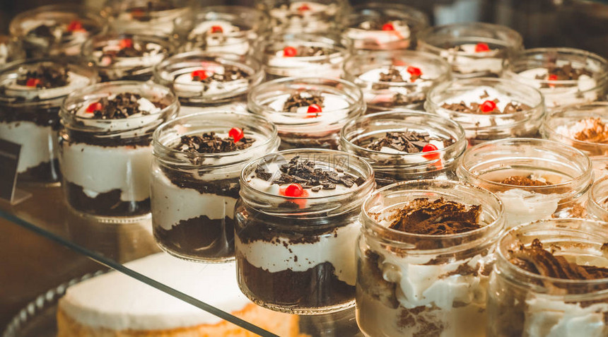 很多美味的甜点放在一个温馨咖啡厅窗户上的罐子里图片