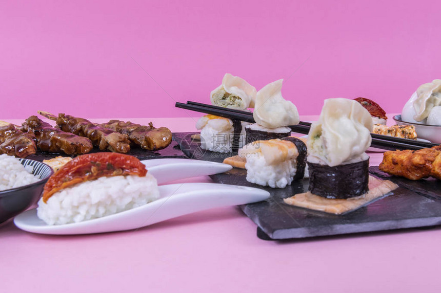 黑色寿司板上的三文鱼和寿司卷在粉红色背景下欣赏图片