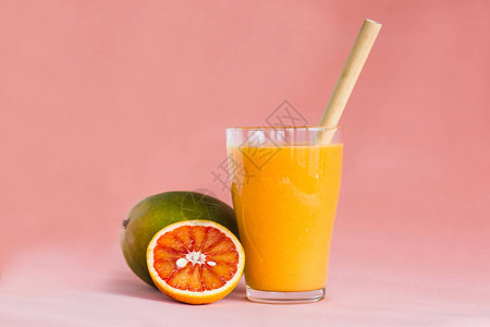 杯芒果和橙汁粉红色背景茶点和夏季饮品维生素和矿物质的概图片