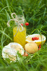 一瓶自制柠檬汁和樱桃及柑橘水果在草地外方图片