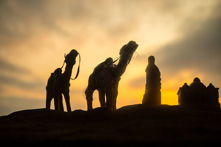 日落时穿过沙漠丘的骆驼大篷车东部旅行概图片
