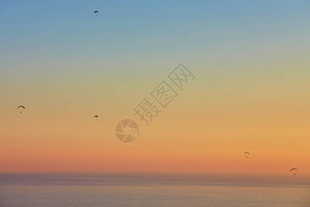 动力滑翔伞在大海上空翱翔的剪影图片