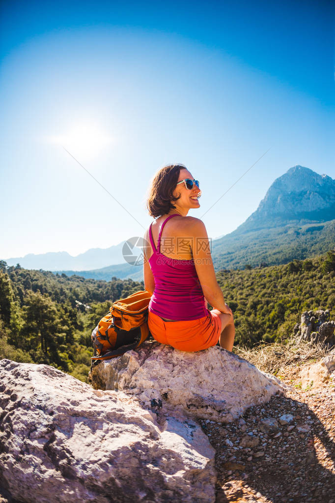 山顶的女孩一个背着包的女人站在岩石上爬到顶部前往风景如画的地方黑发女郎看着地平线土耳其风景图片