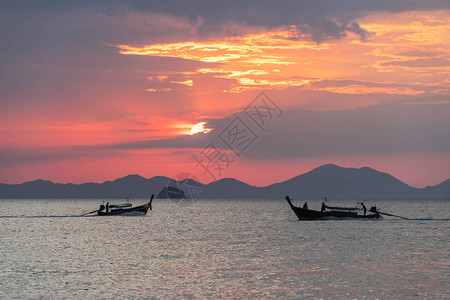 当地长尾小船在海边美丽的日落时漂浮在水中图片