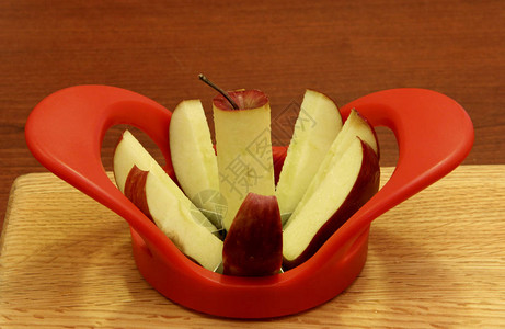 红苹果在木制切菜板上切割和取芯图片