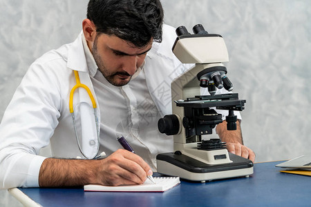 年轻的男医生在医院实验室使用显微镜工作医疗和医药图片