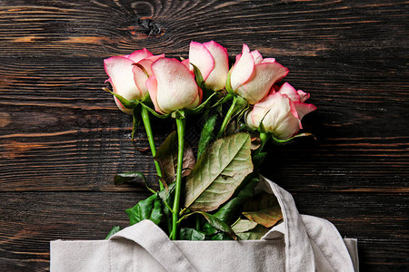 木桌上放着新鲜玫瑰的环保袋图片