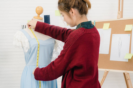 专业美丽的亚洲女时装设计师在工作室为人体服装设计测量礼服生活方式图片