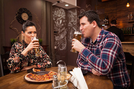 快乐的情侣喝啤酒吃比萨图片