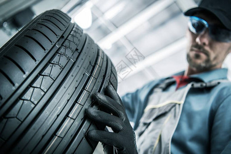 汽车工人用新轮胎更换汽车轮胎背景图片