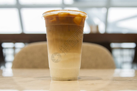 不加奶油的冰焦糖拿铁咖啡在大棕褐色桌子上举杯图片