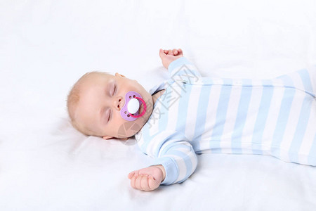 有安抚奶嘴的男婴睡在白床上图片