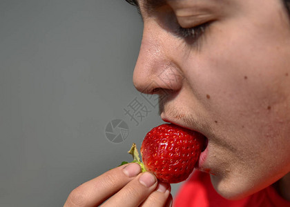 一个正在吃草莓的高加索儿童的特写镜头图片