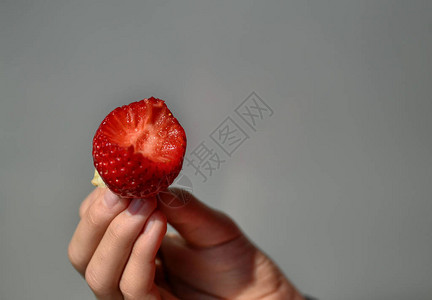 白种男孩的手指支撑着一根草莓图片