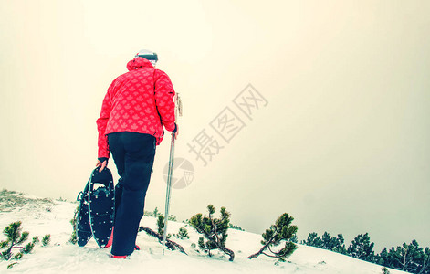 在雪路上穿雪鞋的男人穿着雪鞋和登山杖的图片