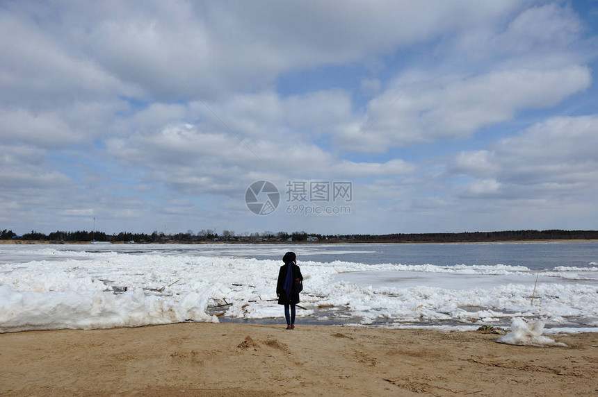 一个戴着帽子的女孩的身影站在维切格达河岸边在冰流图片