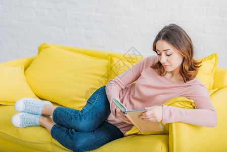 美丽的年轻女子在家睡在黄色沙发图片