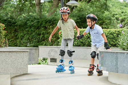 亚裔女孩和男孩手牵在路上骑滑雪溜冰同图片