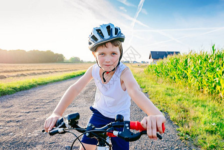 白色头盔骑他的自行车的小孩男骑背景图片